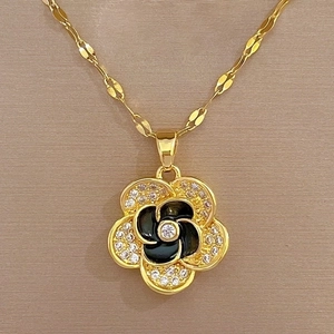 Macro shot of gold floral necklace pendant with black enamel and micro-pave crystals