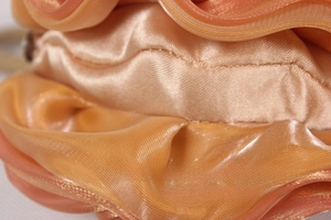 Detailed macro view of the layered silk flower petals and stitching on a satin handbag