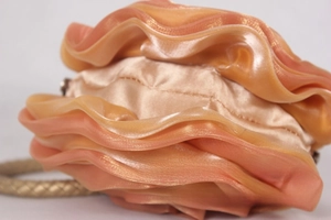 Detail of peach silk floral handbag showing 3D petal texture and satin finish