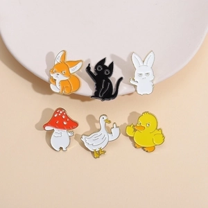 Detail of six funny cartoon enamel pins with animals showing middle finger on beige background
