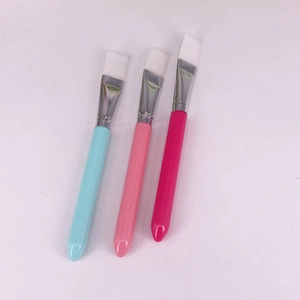 Three colorful facial mask brushes with teal pink and magenta handles on white background