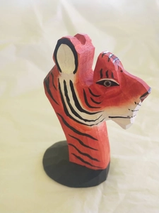 Close-up of hand-carved wooden tiger glasses holder with red stripes on a black base