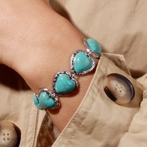 Detailed view of vintage heart-shaped turquoise bracelet with embossed silver metal