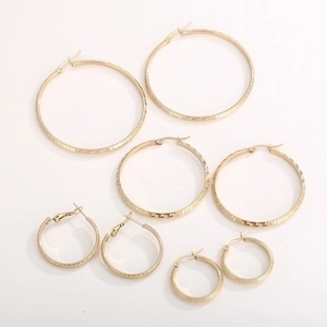 Close-up of four pairs of gold-plated hoop earrings with Greek key pattern engraving