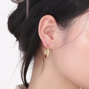 Detailed view of gold plated stainless steel hoop earrings with diamond pattern on model