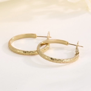 Detailed view of gold plated stainless steel hoop earrings with diamond pattern texture