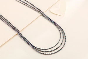 Close-up of rainbow plated stainless steel twisted rope chains on beige background