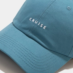 Detailed close-up of CRUISE letter embroidery on blue cotton baseball cap fabric