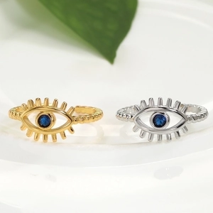 Dettaglio macro di anelli regolabili malocchio oro e argento con zircone blu intarsiato