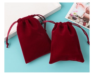 Detailed view of burgundy velvet drawstring jewelry pouches on a blue surface