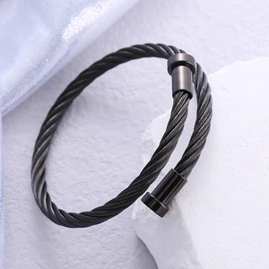 Minimalistisches schwarzes gedrehtes Edelstahl-Armreif-Armband auf weißem Stein