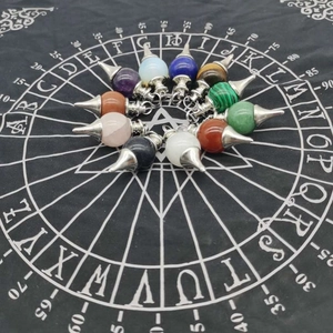 Radial layout of various natural crystal pendulum pendants on a black divination cloth