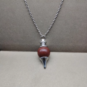 Detailed view of reddish-brown stone pendulum pendant with a silver metal cone base