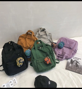 Flat lay of colorful canvas backpacks with check cap pendants and retro accessories