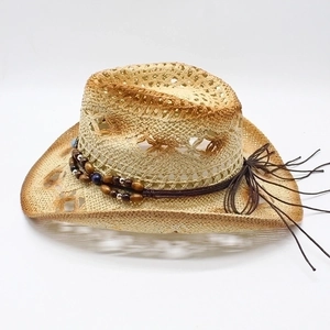 Cappello da cowboy in paglia traforata con perline etniche in legno su sfondo bianco
