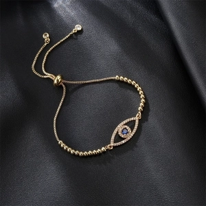 Detailed top view of gold Evil Eye bracelet with blue gemstone on black leather texture