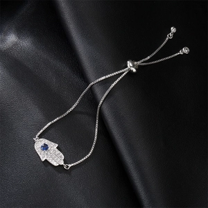 Silver Hamsa Hand bracelet with blue cubic zirconia on black leather background