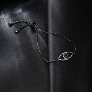 Macro detail of evil eye bracelet with blue zircon inlay on textured black background