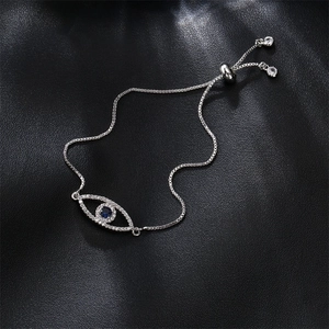 Silver evil eye bracelet with blue zircons and adjustable sliding clasp on black texture