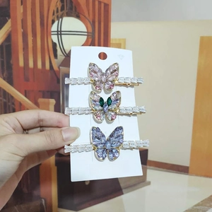 Detailed view of three Korean butterfly hair clips with zircon crystals on a jewelry card