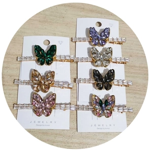Flat lay of six colorful rhinestone butterfly hair clips on a wooden background