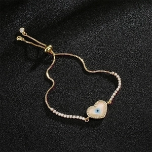 Detail of gold heart bracelet with evil eye zircon inlay and adjustable slider clasp