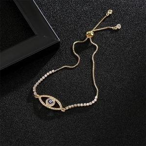 Detail of gold evil eye bracelet with blue and white zircon stones on black background