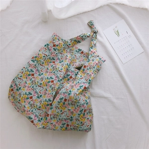 Detail of floral cotton tote bag featuring knotted shoulder strap on white fabric