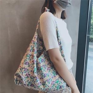 Close-up of a large capacity purple floral cotton tote bag worn by a model in casual style