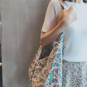 Detailed view of purple floral canvas tote bag worn by model on a grey background