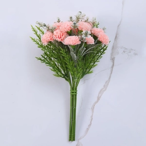 Detail of pink silk carnations with green pine needles on white marble background