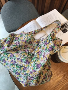 Macro shot of large purple floral cotton tote bag on a wooden table with lifestyle props