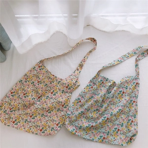 Detail view of cream yellow and light blue floral cotton tote bags in a soft aesthetic