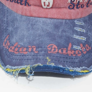 Macro detail of washed cotton baseball cap with vintage embroidery and frayed brim edge