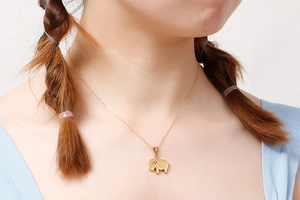 Close-up of a gold elephant pendant necklace worn by a model for a delicate jewelry look