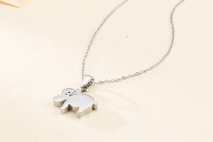 Detailed view of a polished silver elephant pendant necklace on a beige surface