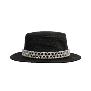 Eleganter schwarzer Strohhut mit flacher Krone, weißen Perlen und Sonnenschutz am Strand