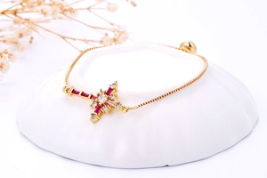 Detail van gouden schakelarmband met regenboog kruishanger en verstelbare schuifsluiting