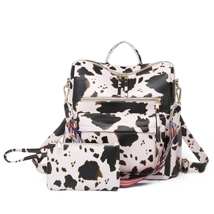 Detail of cow print backpack and matching small pouch with colorful woven shoulder strap