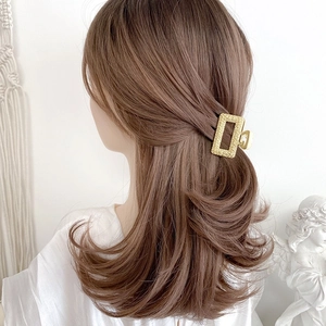 Detail of champagne gold rectangular metal hair claw clip with textured hammered finish