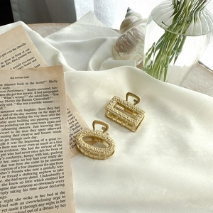 Macro shot of rectangular and oval gold metal hair clips with granulated matte texture