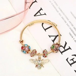 Detailed shot of golden spiral bead bracelet with colorful rhinestones and bee pendant