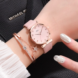 Gros plan d'une montre en cuir rose avec boîtier or rose et bracelet à breloque étoile