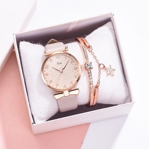 Détail de montre à quartz or rose avec bracelet cuir rose et bracelet étoile en coffret