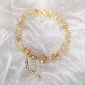 Natural irregular citrine crystal bracelet with gold clasp on white faux fur background