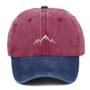 Detailed close-up of mountain embroidery on a washed burgundy and blue baseball cap