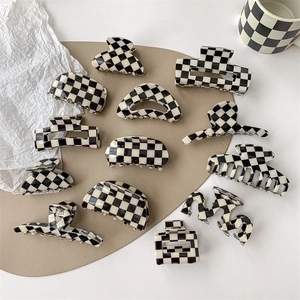 Various black and white checkered hair claws in rectangular and wavy styles on a desk