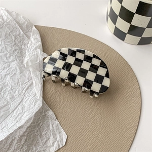 Close-up of black and white checkered hair claw clip with glossy finish and curved teeth
