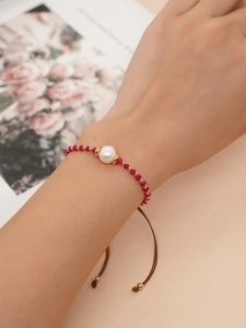 Detail of a handmade red beaded bracelet with white pearl and brown adjustable cord