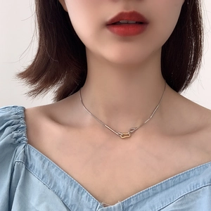 Close-up of minimalist two-tone silver and gold geometric link necklace on a model